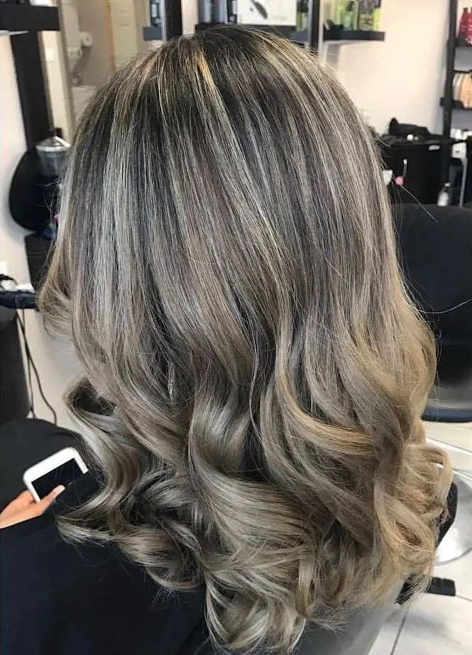 Ash blonde highlights provide a generous amount of brightness to medium-length dark hair